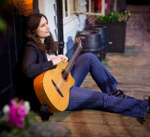 Edina Balczo sitting holding her spanish guitar